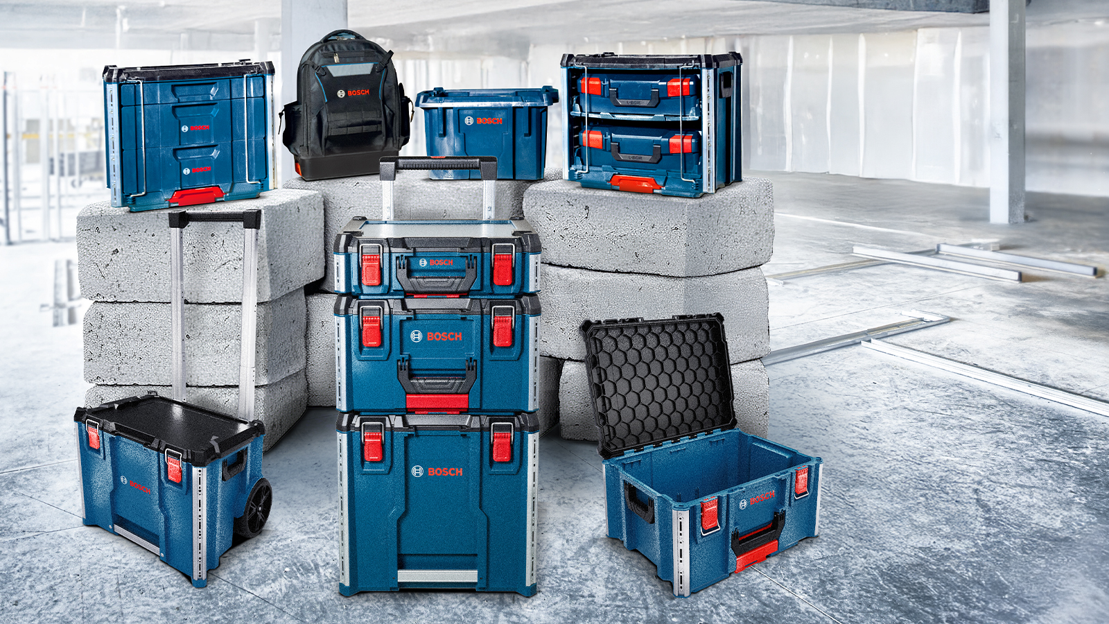 青と黒のさまざまなボッシュプロフェッショナルツールケースが、現代的な空間の灰色のコンクリートブロックの上に置かれています。