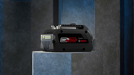 灰色の表面の上にある黒い工具、青と灰色の壁に囲まれています。