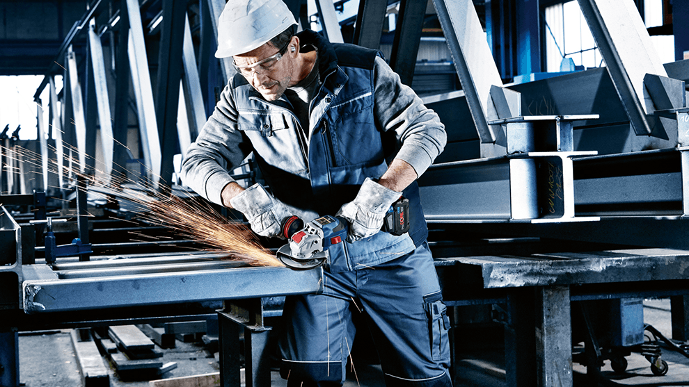 ボッシュの角グラインダーを使って作業員が工房で金属部品を加工しています。