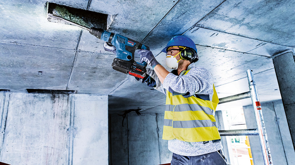 ヘルメットをかぶった作業者が青いボッシュプロフェッショナルツールで穴を開けています。