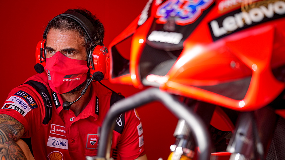 赤い服を着た整備士が赤いバイクの横に座っています。