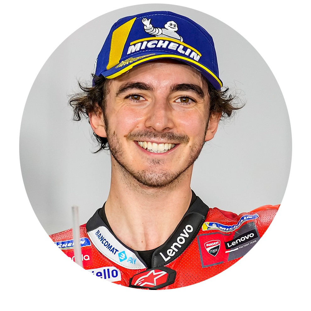 バイクジャケットと青い帽子をかぶった笑顔の男性が友好的にポーズをとっています。