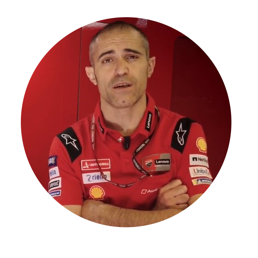 赤いシャツを着た男性が赤い背景の前に立って話しています。