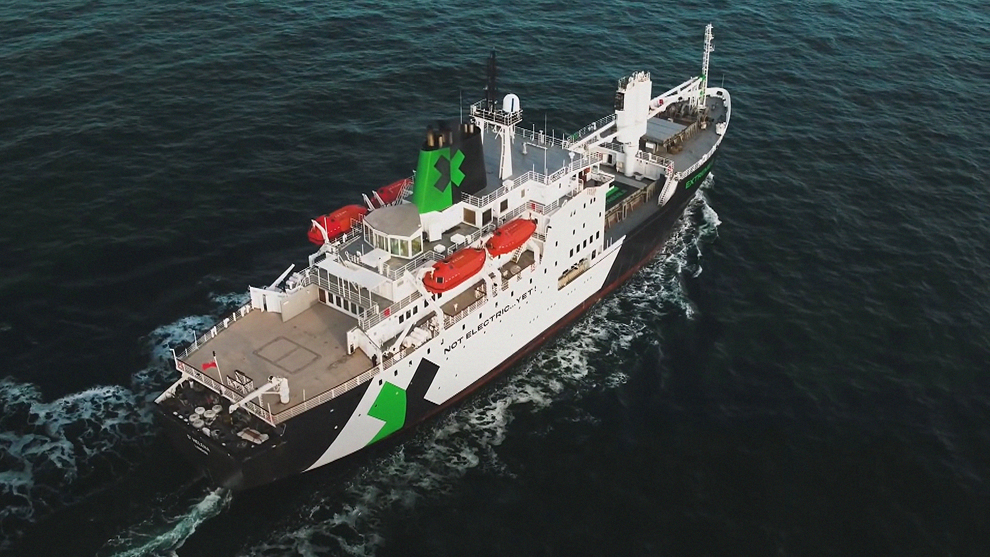 緑のマークが付いた大きな船が青い水の上を航行しています。