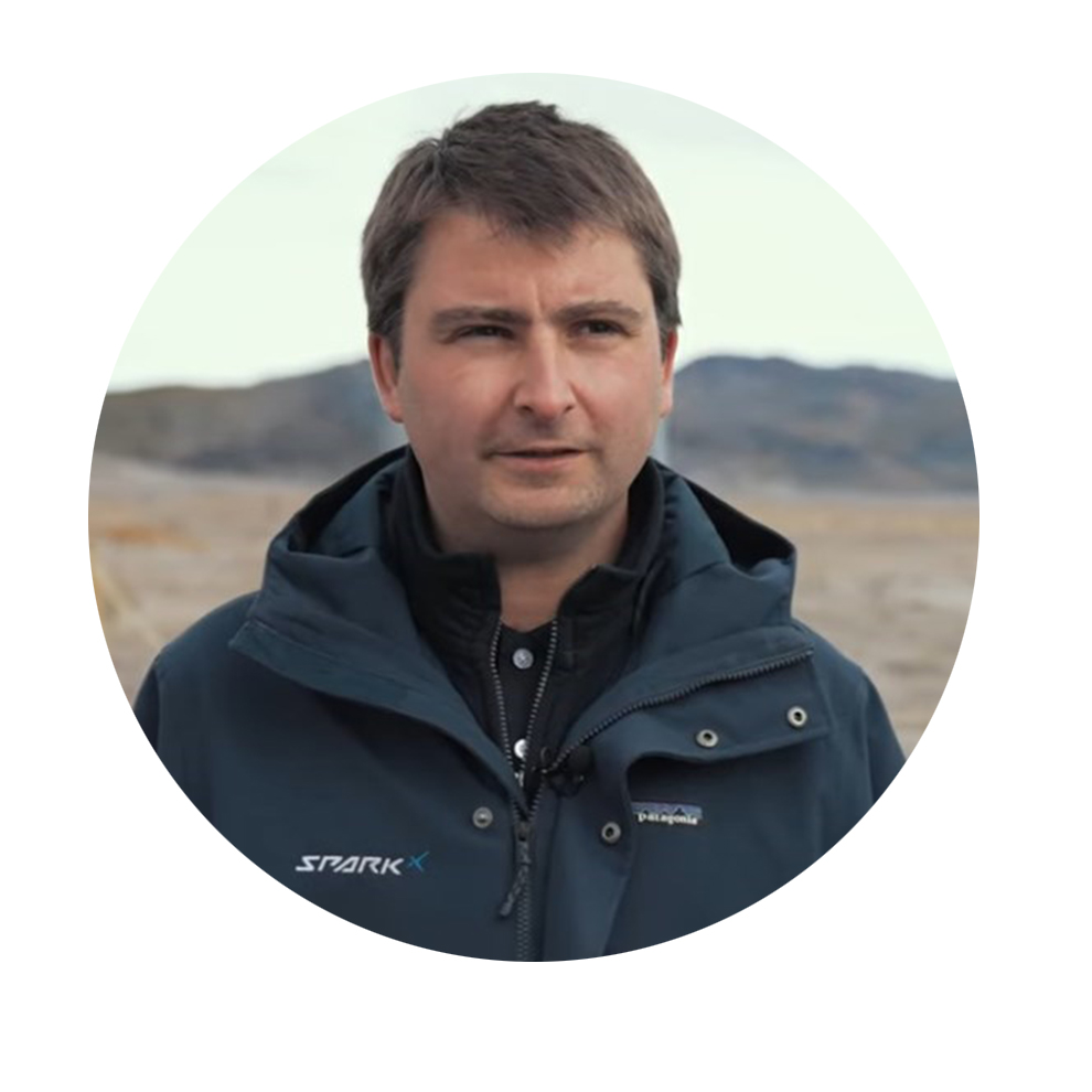 青いジャケットを着た男性が山の風景の前に立ち、考え込んでいます。