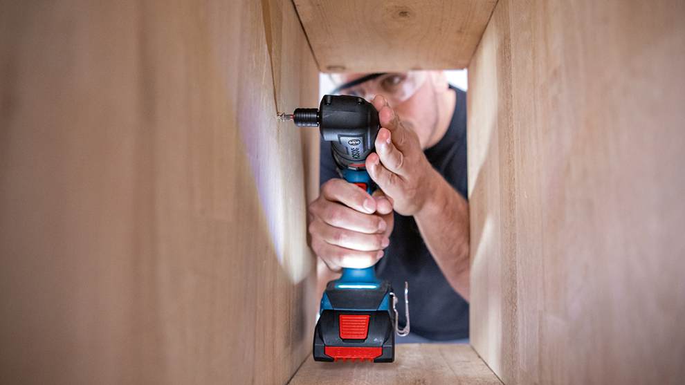 職人が木製フレームでボッシュプロフェッショナルのコードレスドリルを使用しています。