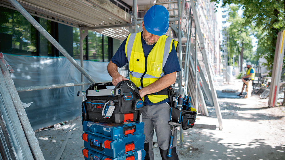青いヘルメットをかぶった建設作業員がボッシュの工具箱で作業しています。