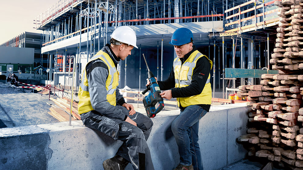 ヘルメットをかぶった2人の建設作業員がボッシュの工具について話し合っています。