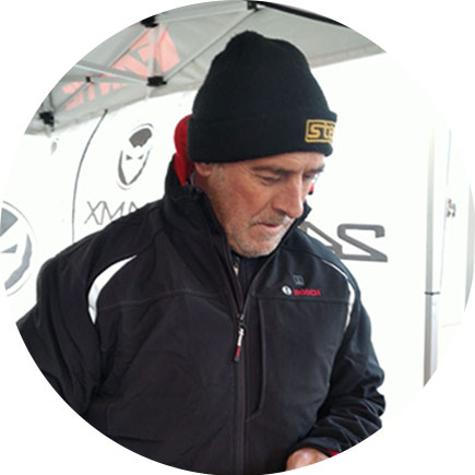 黒いジャケットと帽子をかぶった男性がテントの下に立っています。