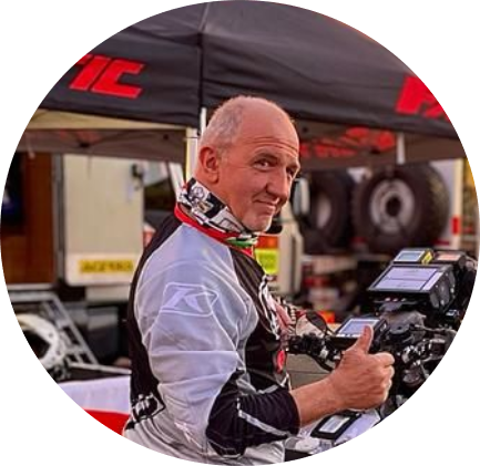 レースウェアを着た男性がテントとバイクの前でサムズアップしています。