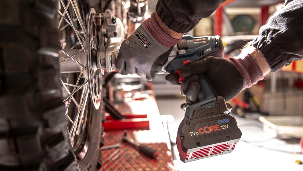 職人がバイクのタイヤにボッシュプロフェッショナルのコードレスドライバーを使用しています。