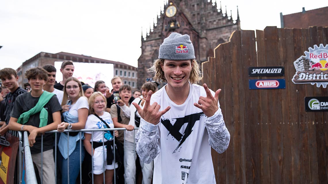 カジュアルな服装の若い男性が群衆の前でポーズをとっています。