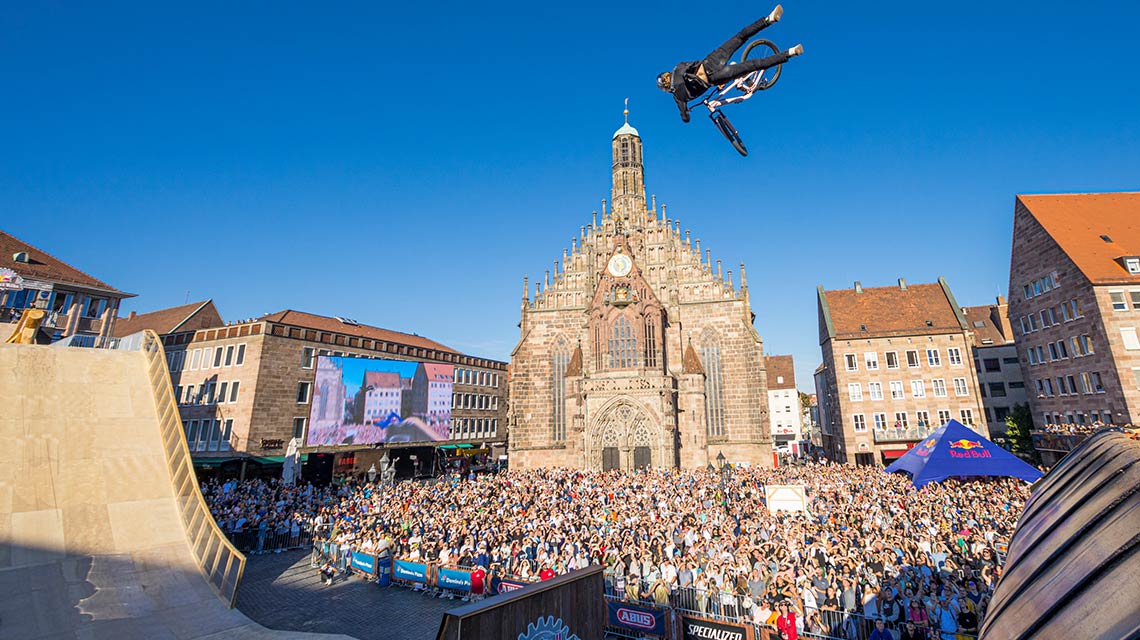 自転車に乗った人が大勢の前でランプを飛び越えています。