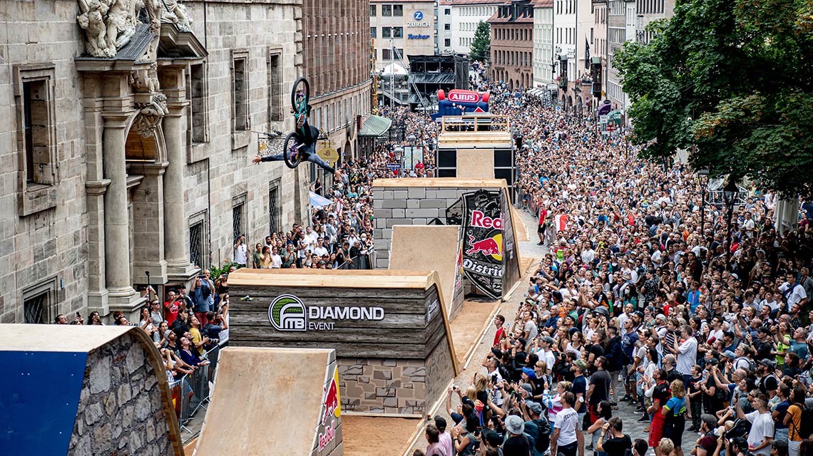 BMXライダーが大勢の観衆の前でランプを飛び越えています。