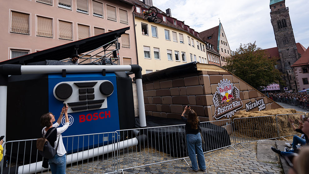 観客、スタントバイク、歴史的建物を背景にしたボッシュの広告設置。