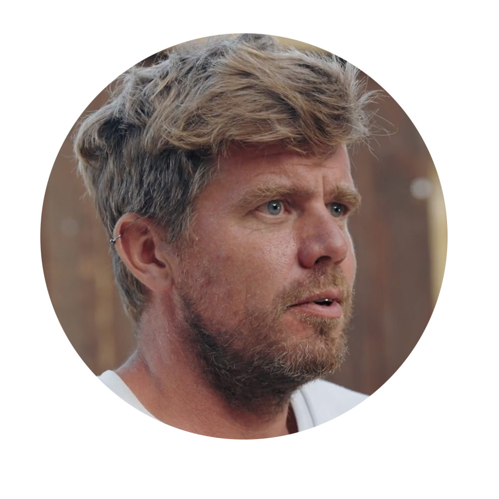 金髪とひげの男性が考え込んでいる。