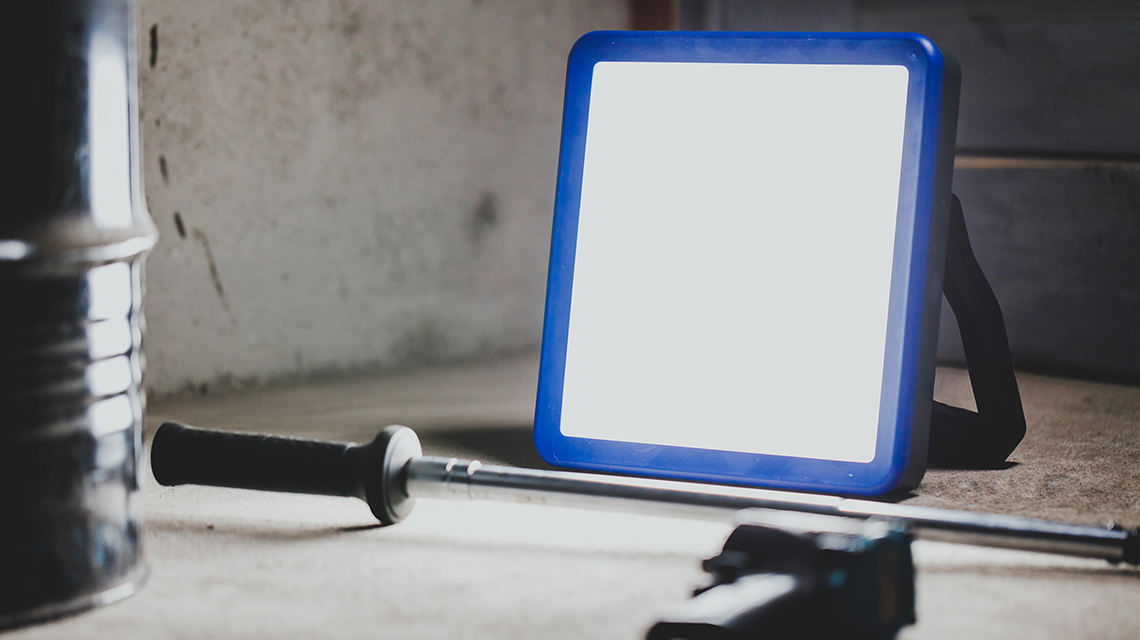 青い建設用ランプが金属容器と工具の横に置かれています。