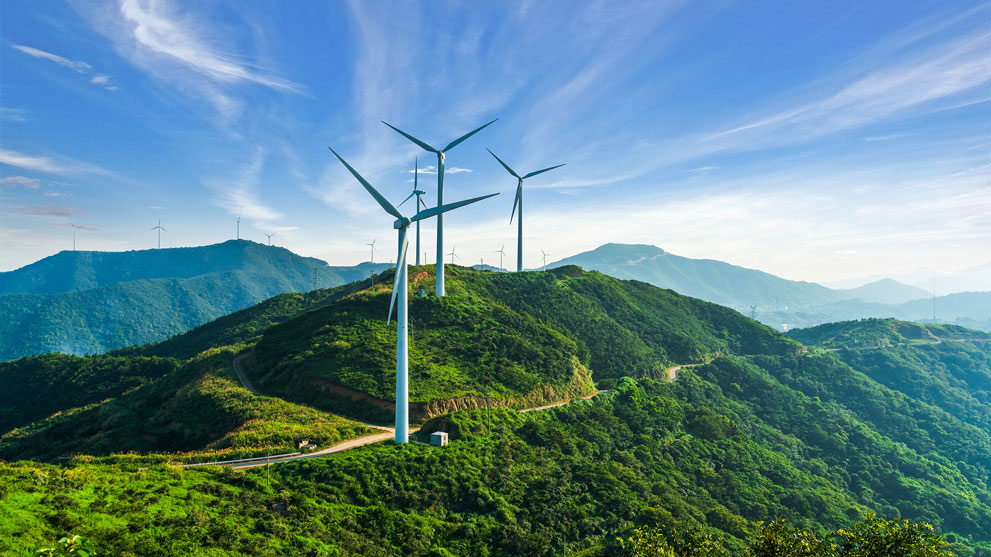 風力発電機が青い空の下、緑の丘に立っています。